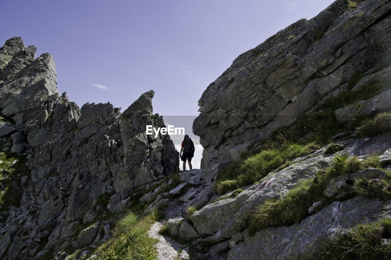 PEOPLE WALKING ON ROCKS AGAINST MOUNTAIN
