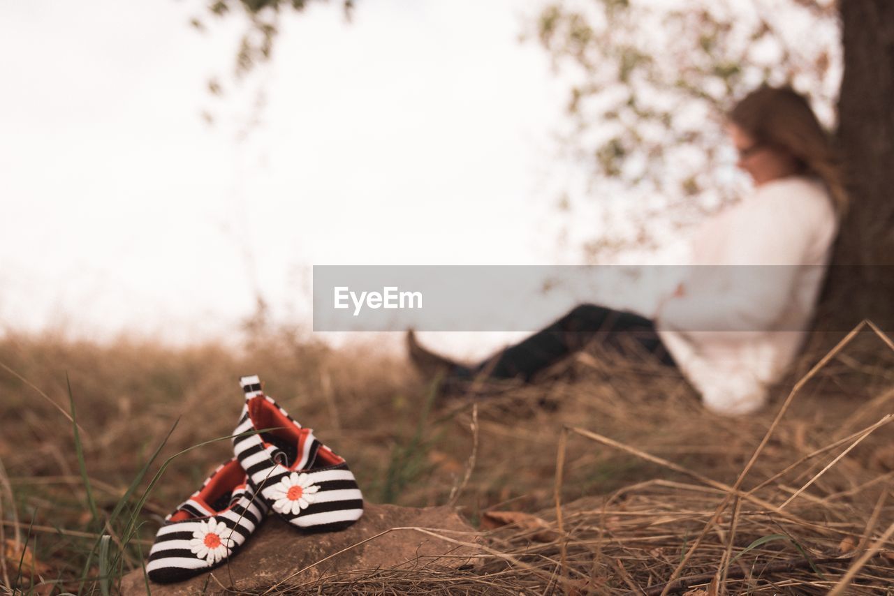 Close-up of shoes with woman sitting in background