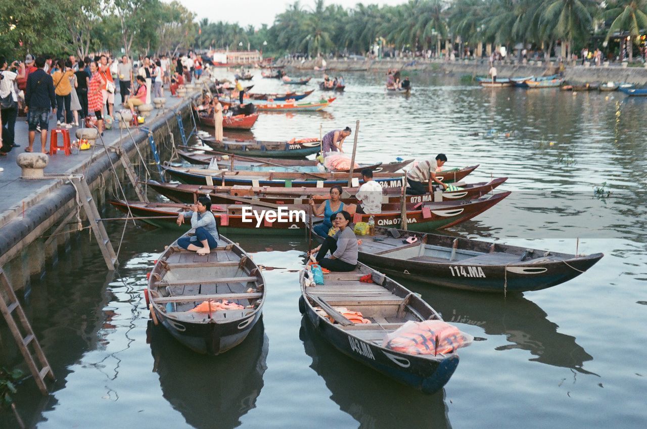 PANORAMIC VIEW OF PEOPLE ON BOATS MOORED AT SHORE
