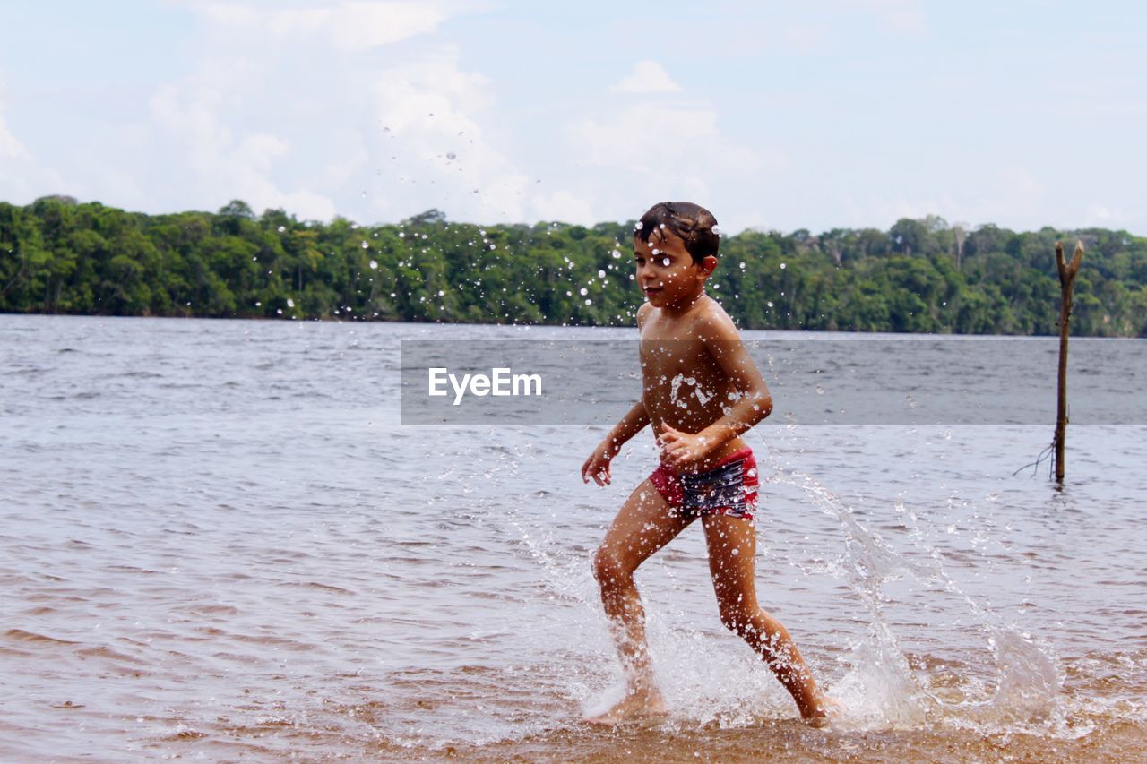 Boy splashing water while playing at beach