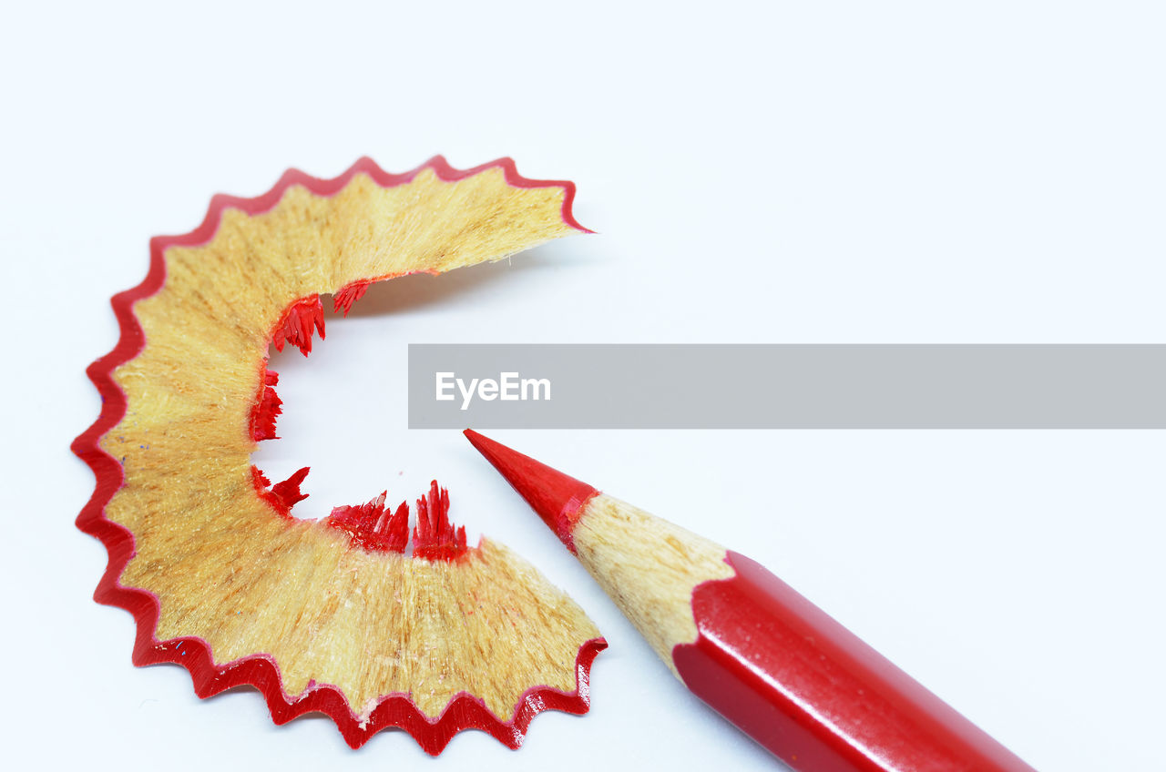 Close-up of colored pencils with shavings against white background