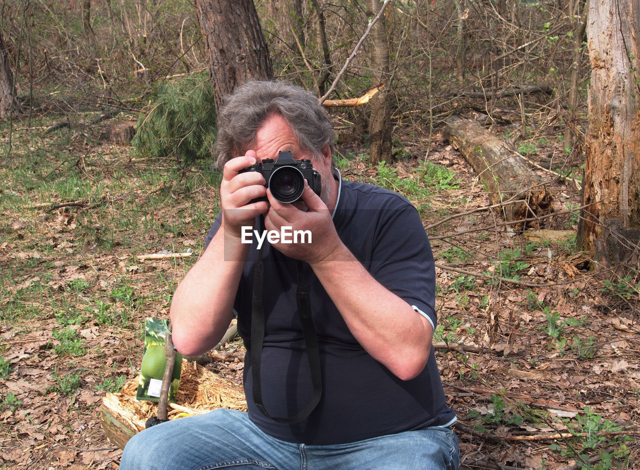 Man photographing while sitting on field