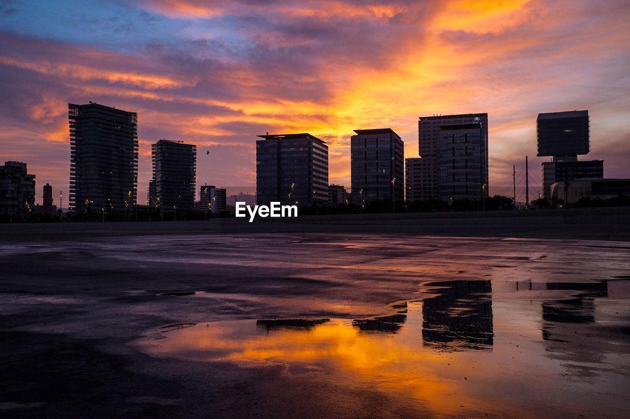 Buildings and street against sky during sunset in city