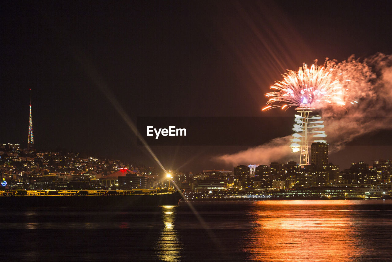 FIREWORK DISPLAY OVER ILLUMINATED CITY AT NIGHT