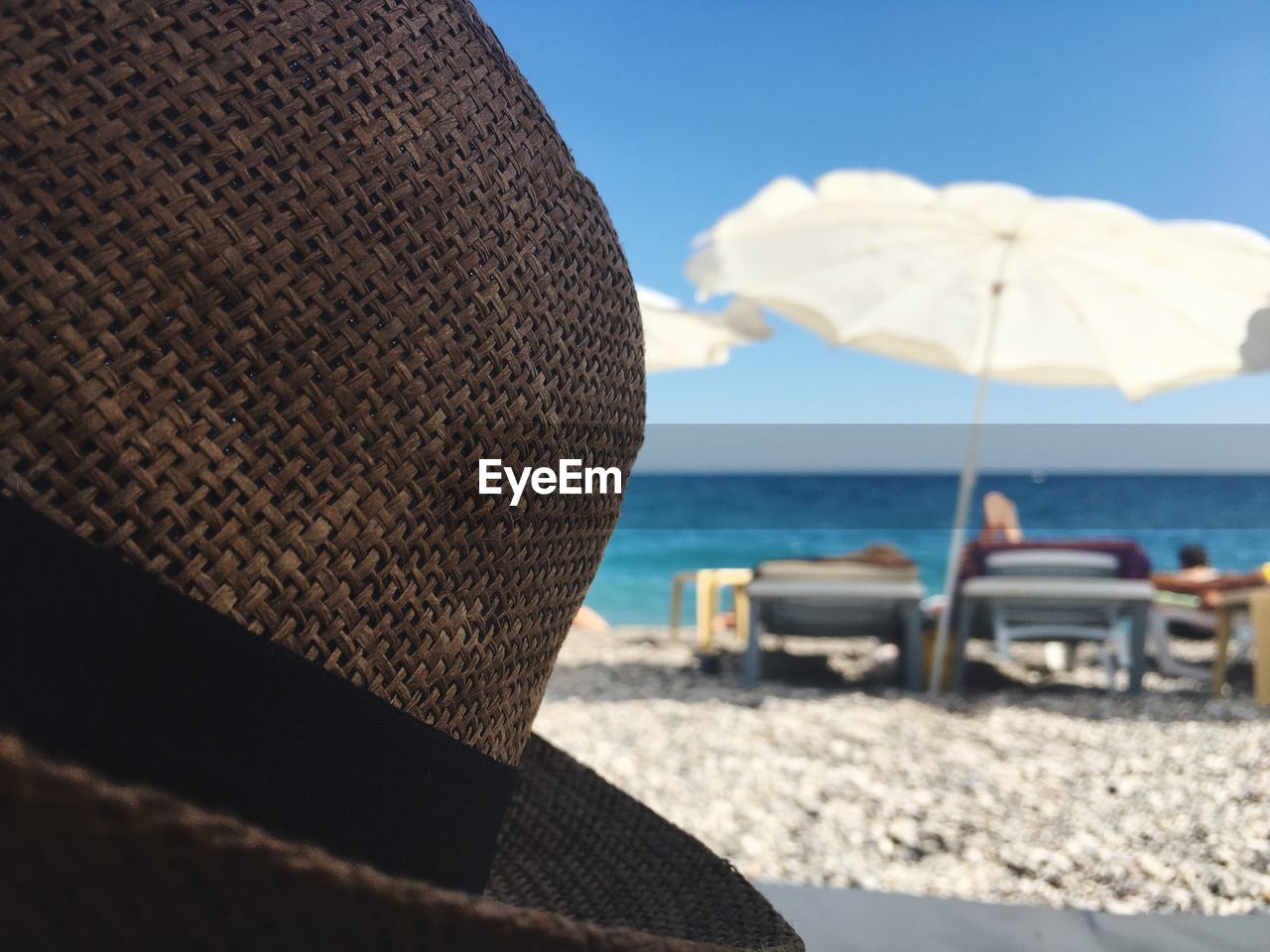 Close-up of sun hat at beach against sky