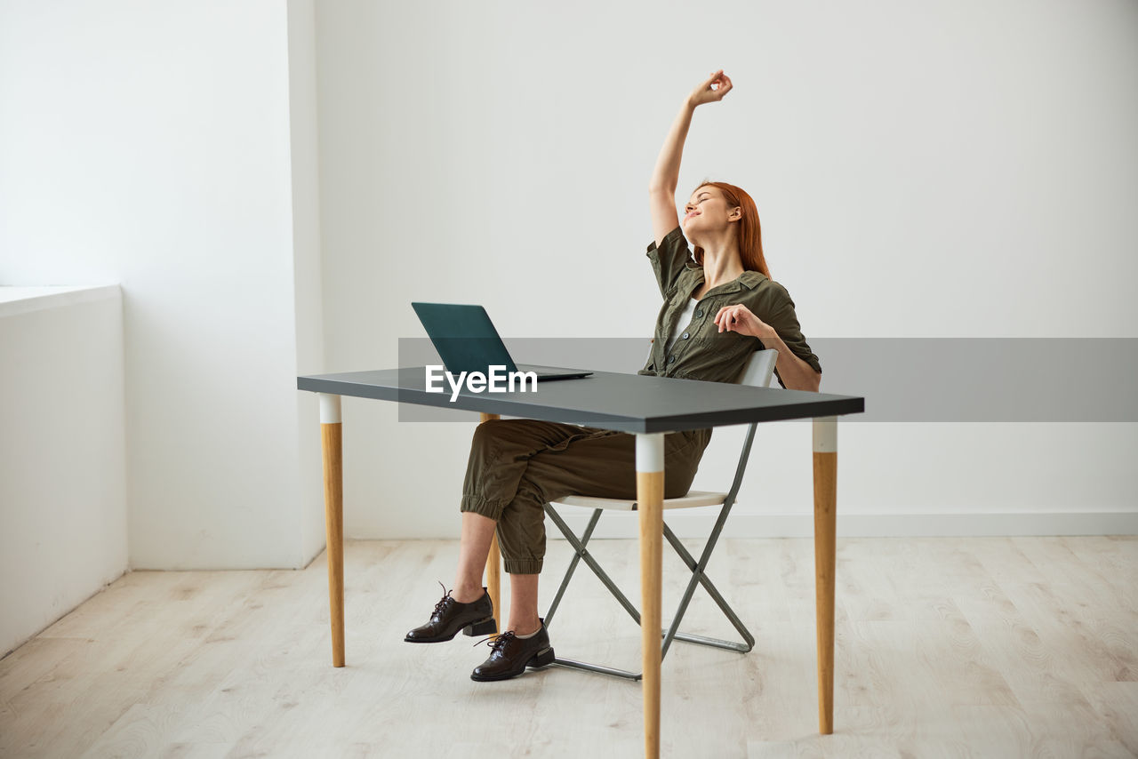 woman using laptop while sitting on table at home