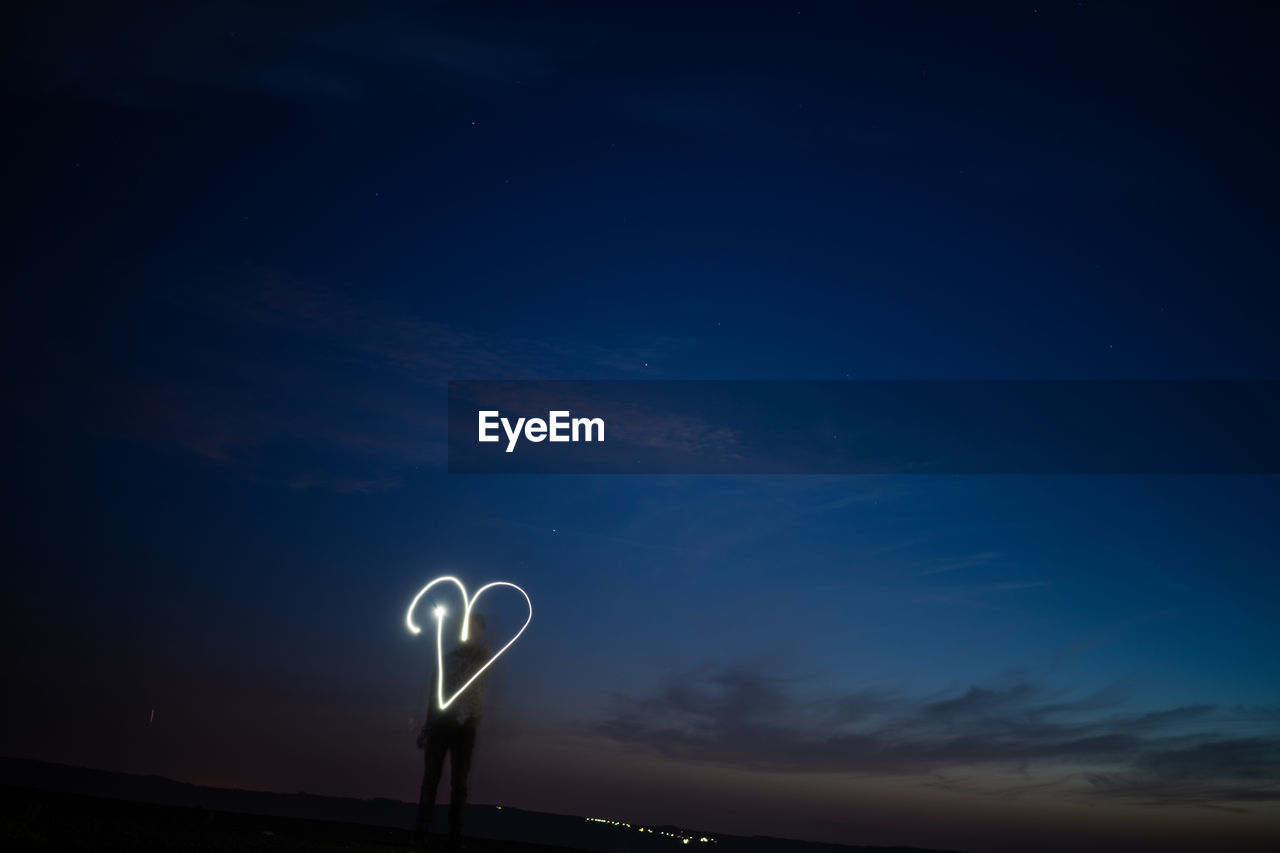 LOW ANGLE VIEW OF ILLUMINATED LAMP AGAINST BLUE SKY