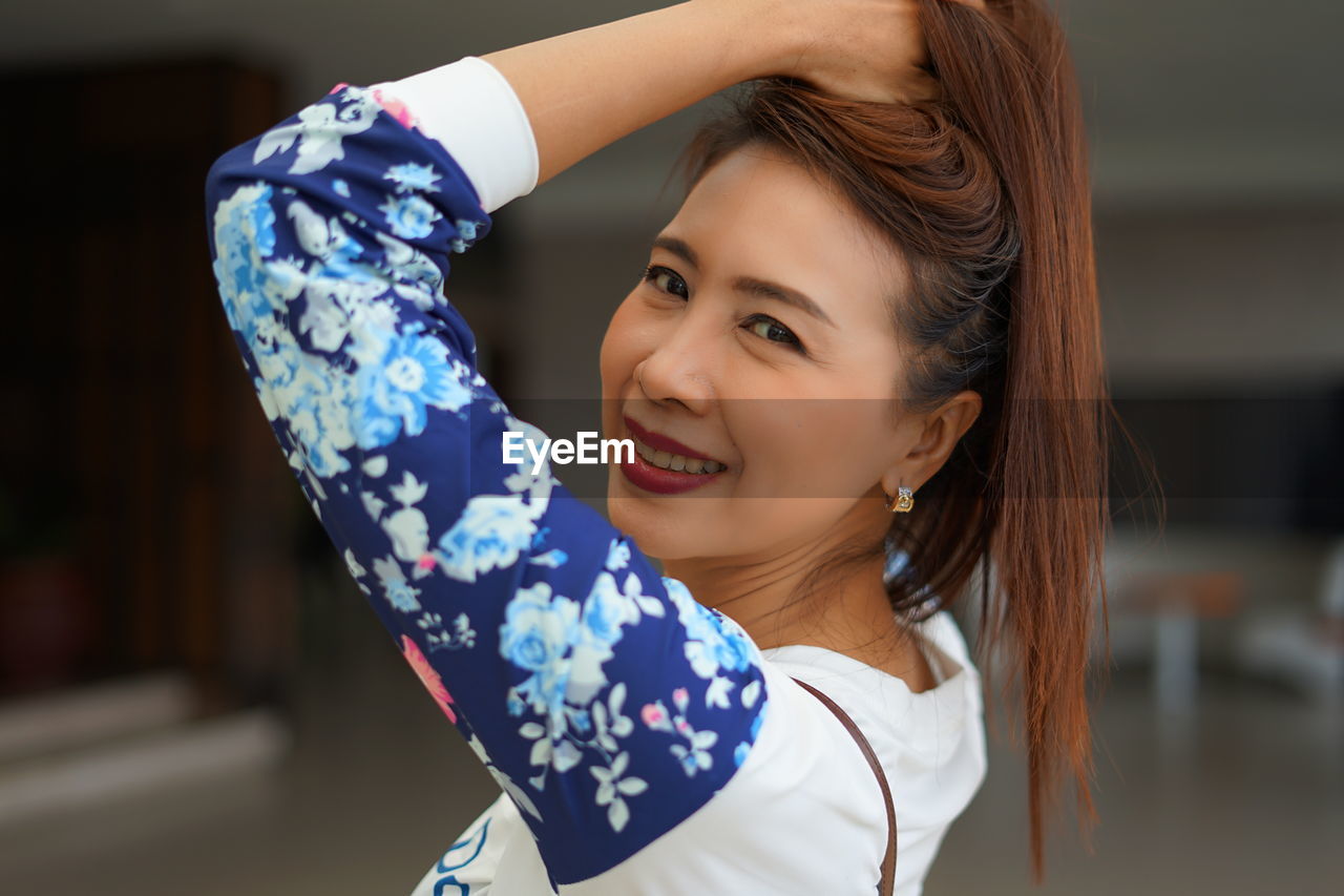 Portrait of smiling woman with hand in hair at home