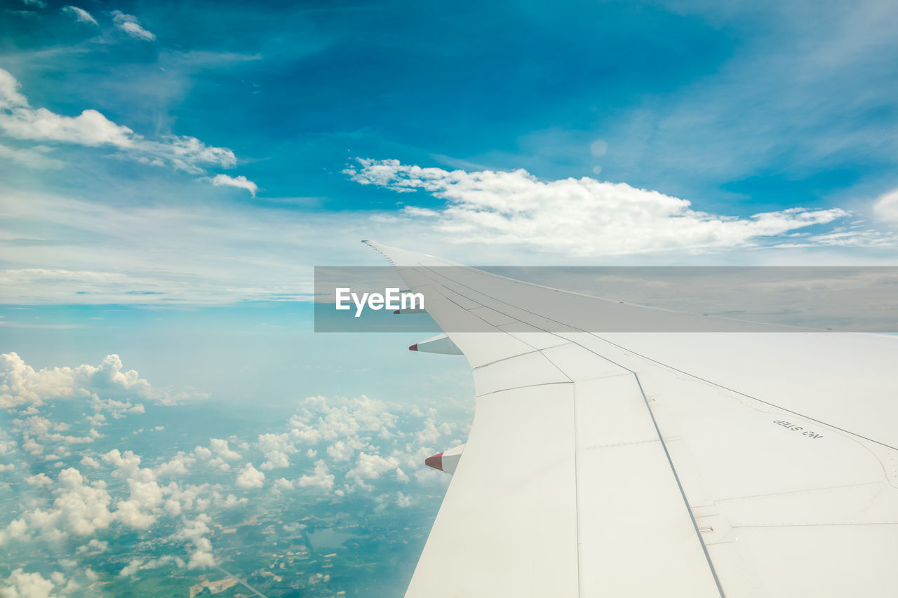 Aerial view from airplane window. airplane flying above land and sea with beautiful cloud in the sky