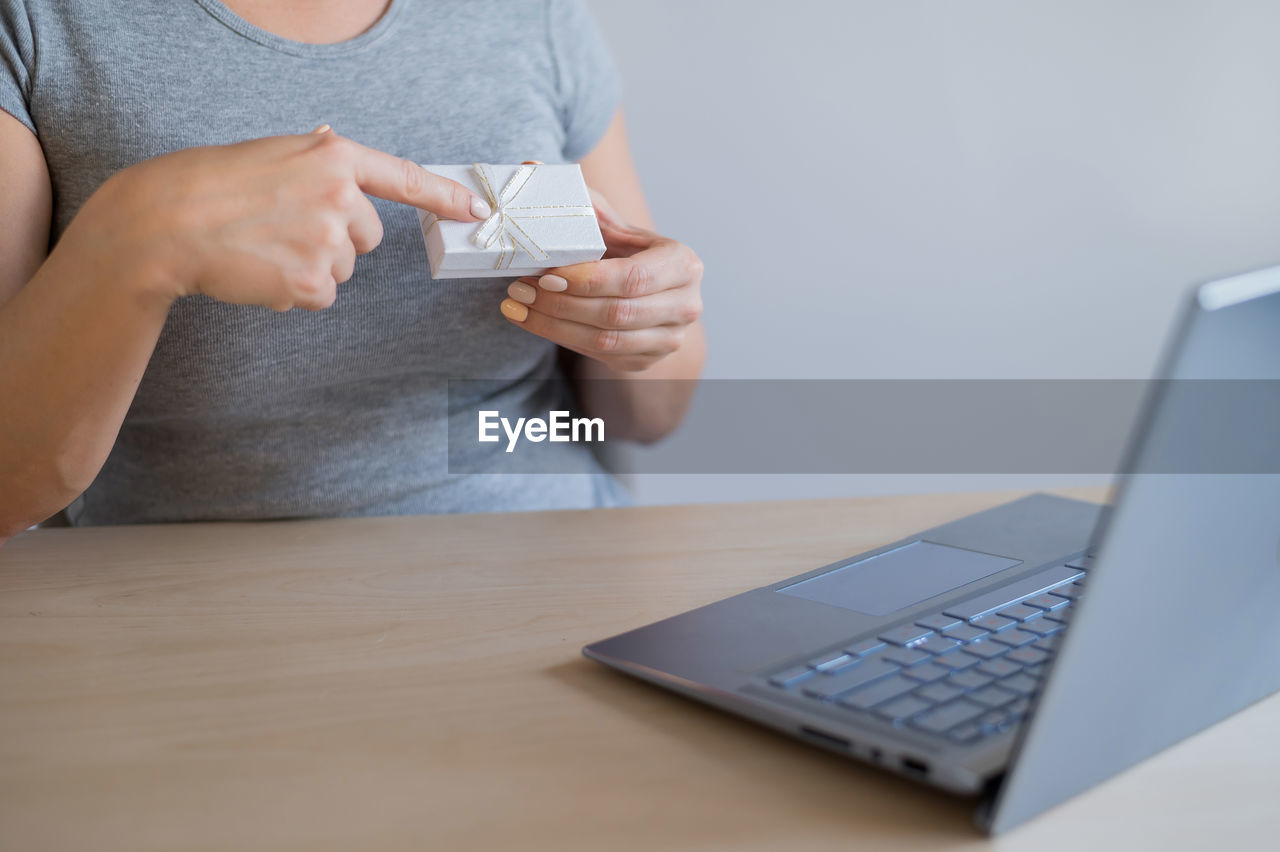 Midsection of woman using mobile phone while sitting on table