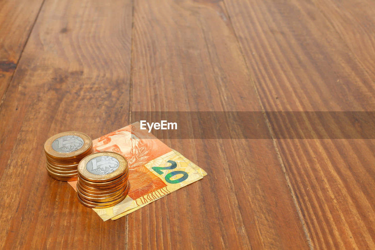 HIGH ANGLE VIEW OF COIN ON WOODEN TABLE