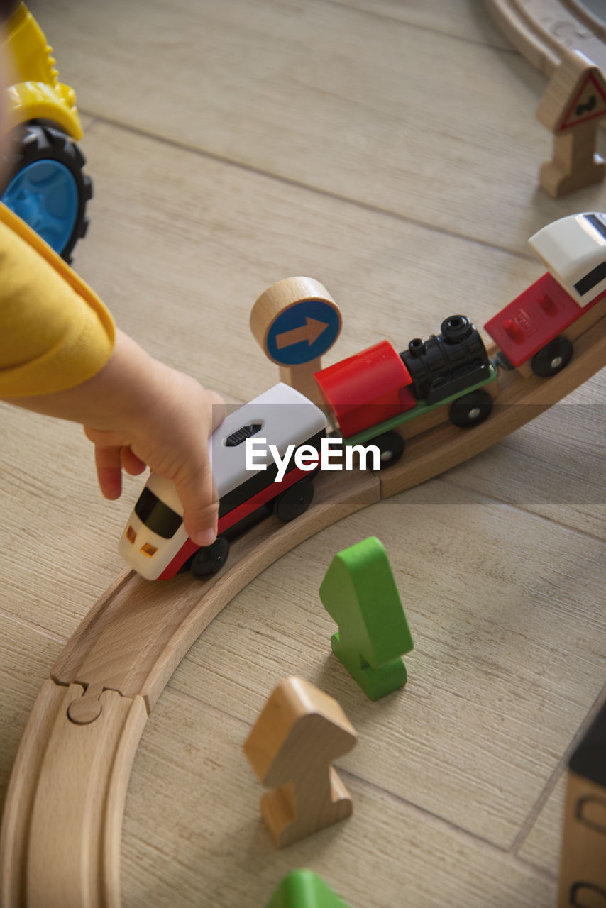 toy, one person, indoors, hand, high angle view, wood, childhood, flooring, sports, yellow, holding