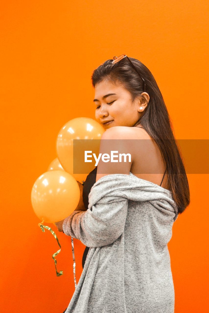 Young woman standing against orange background