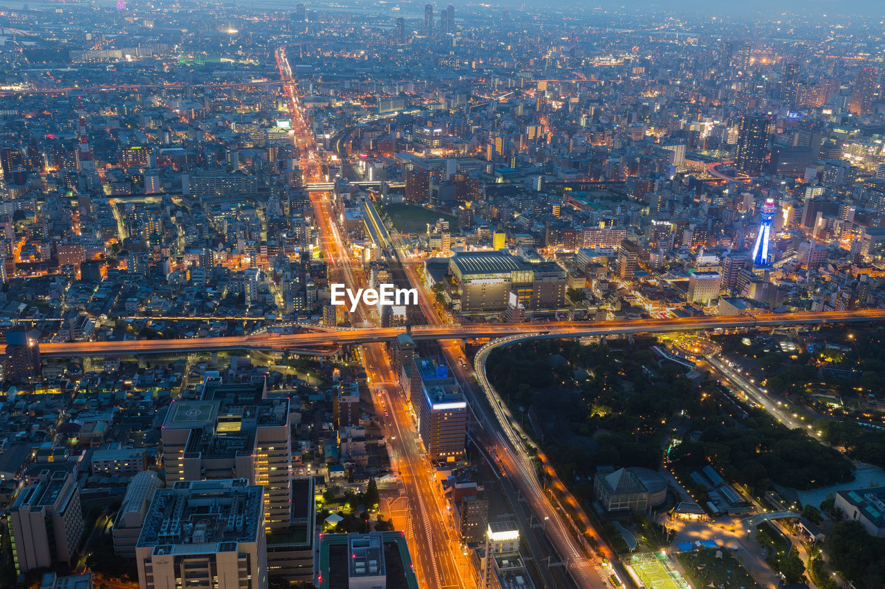 HIGH ANGLE VIEW OF ILLUMINATED CITY STREET AND BUILDINGS