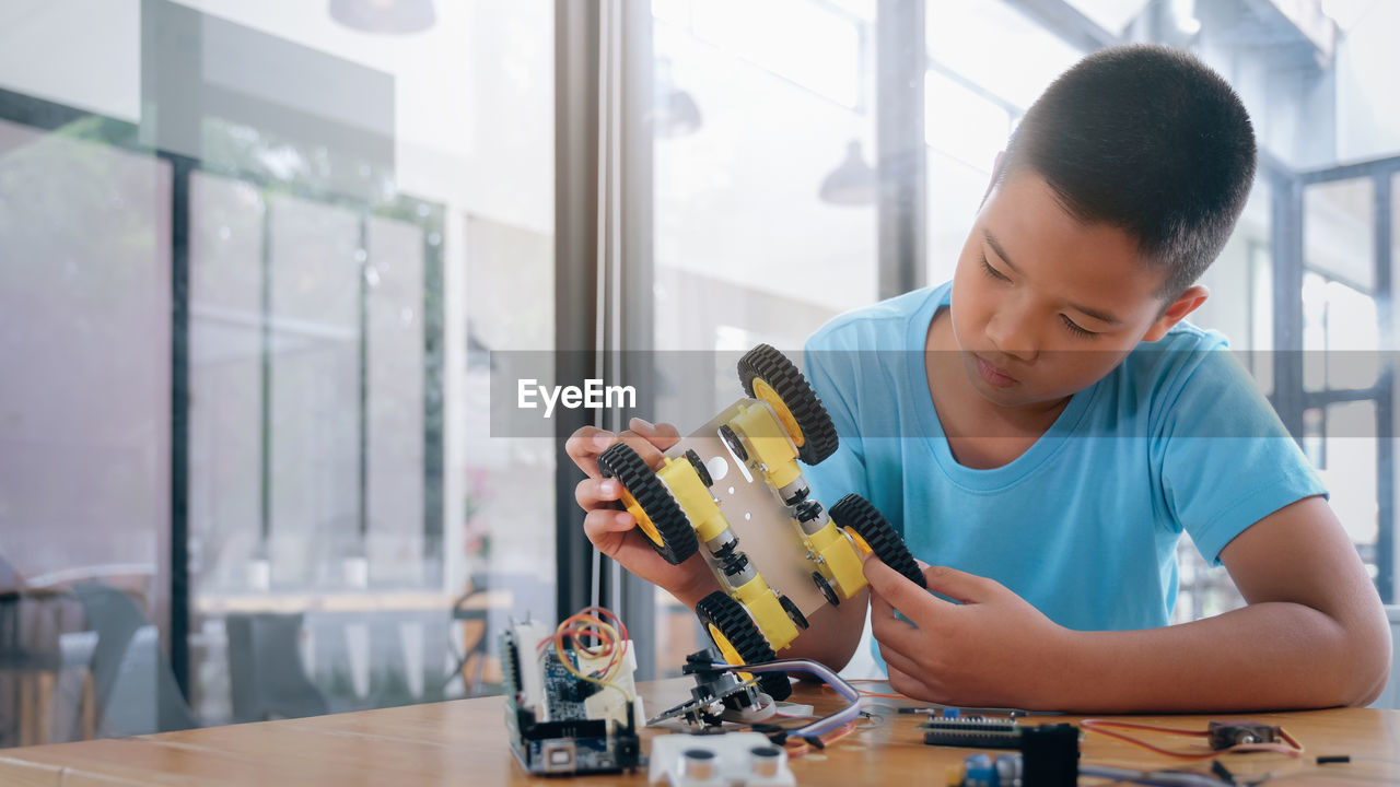 Boy repairing toy on table