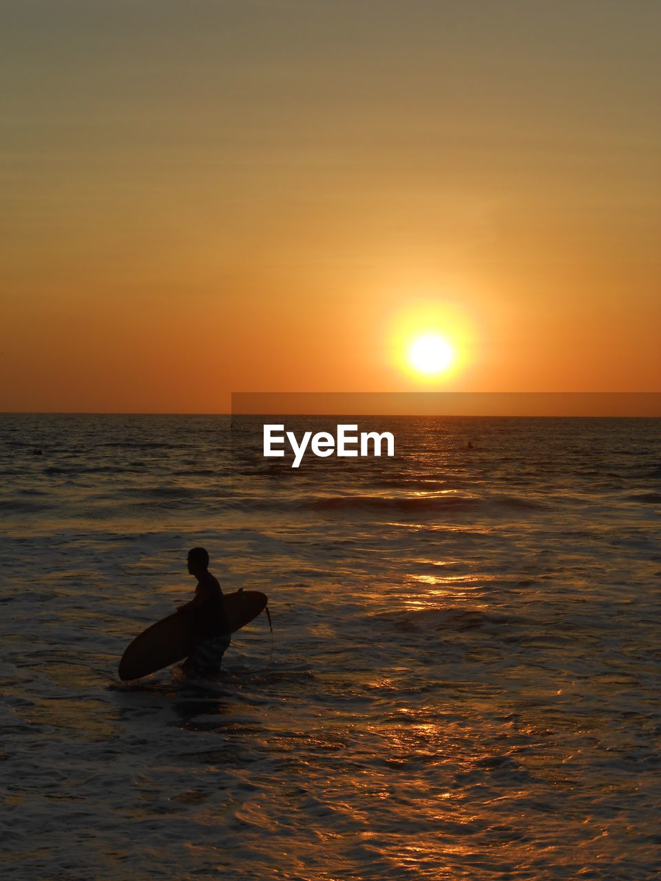 SILHOUETTE MAN ON SEA AGAINST ORANGE SKY