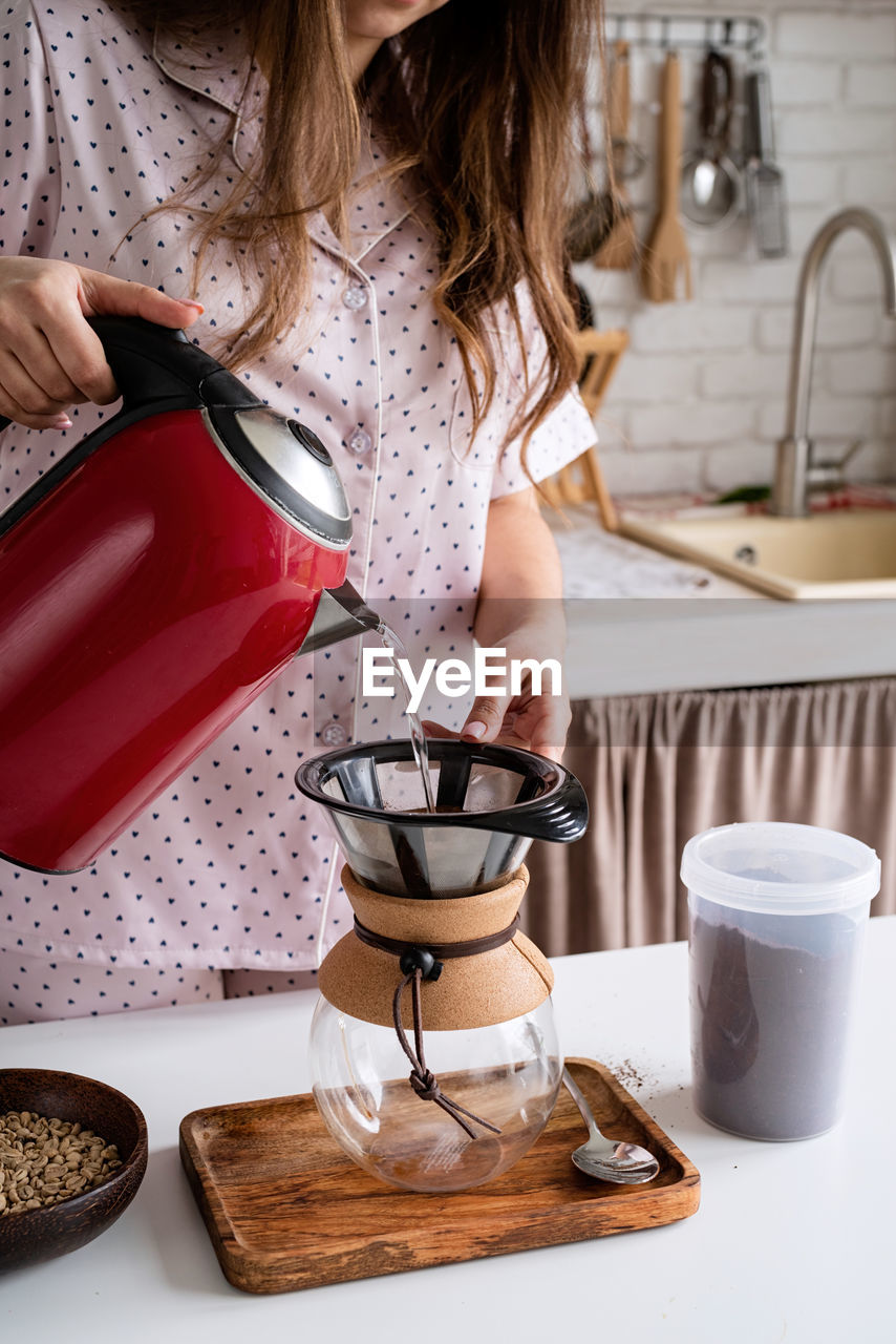 Alternative coffee brewing. young woman in lovely pajamas making coffee at home kitchen