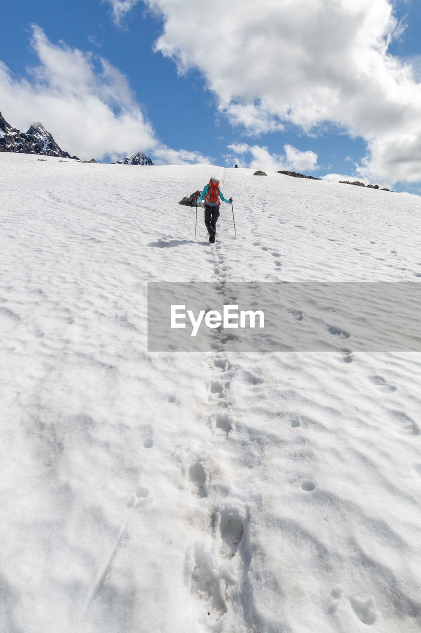 Rear view of person hiking on snowcapped mountain