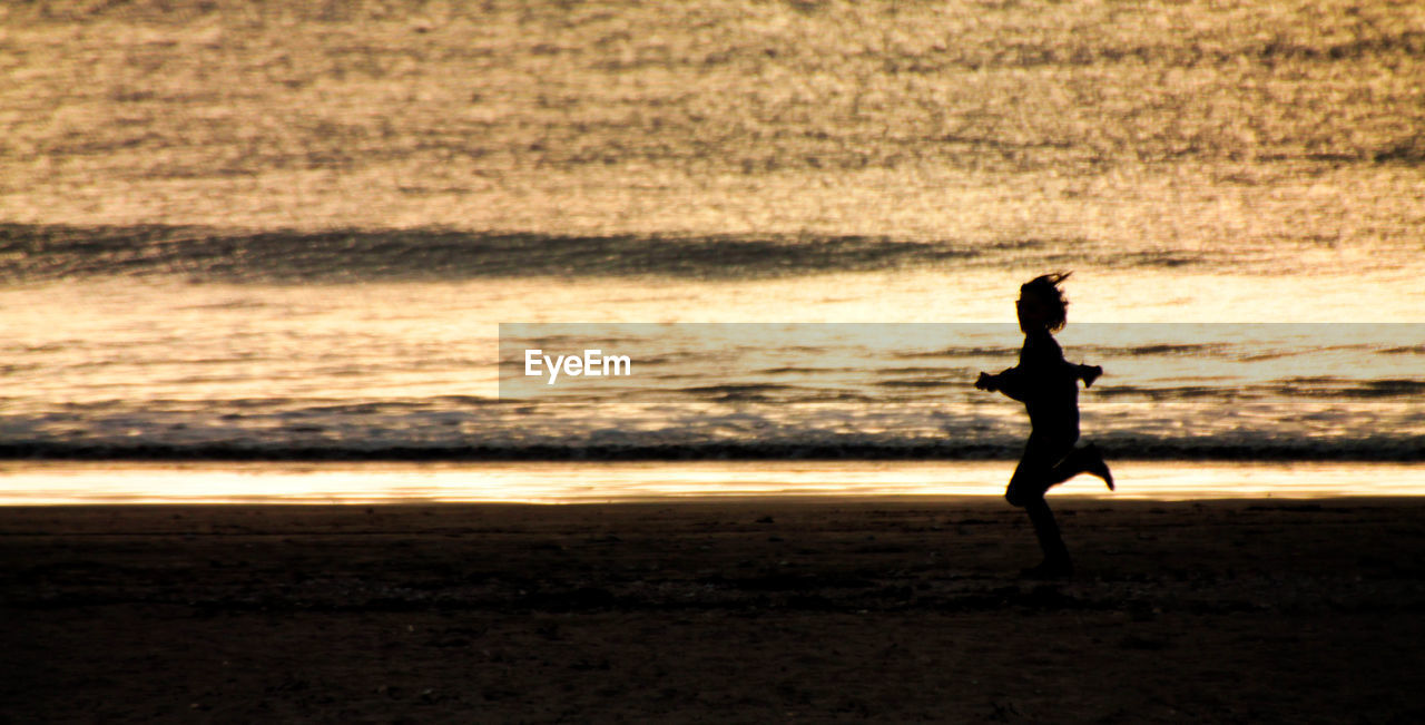 Silhouette person running on beach