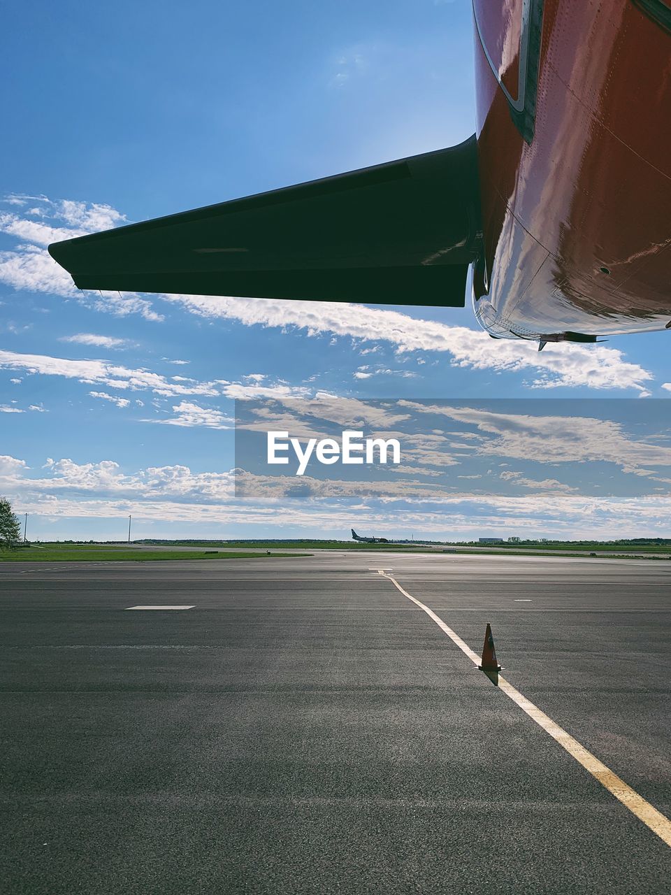 Cropped image of airplane at airport runway against sky