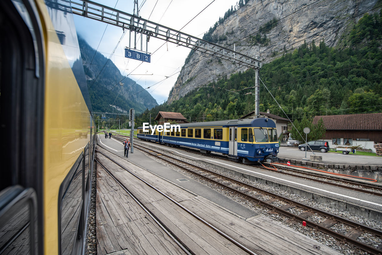 TRAIN ON RAILROAD TRACKS BY MOUNTAIN AGAINST SKY