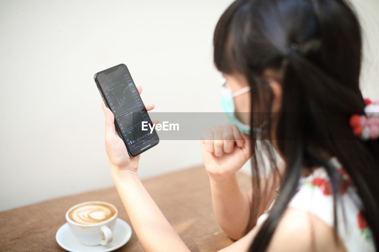 Woman wearing mask using mobile phone at table