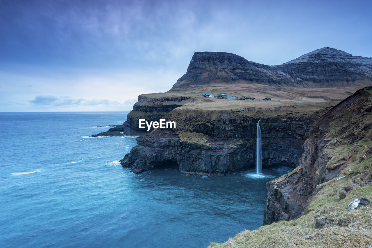 Scenic view of sea and mountains against blue sky