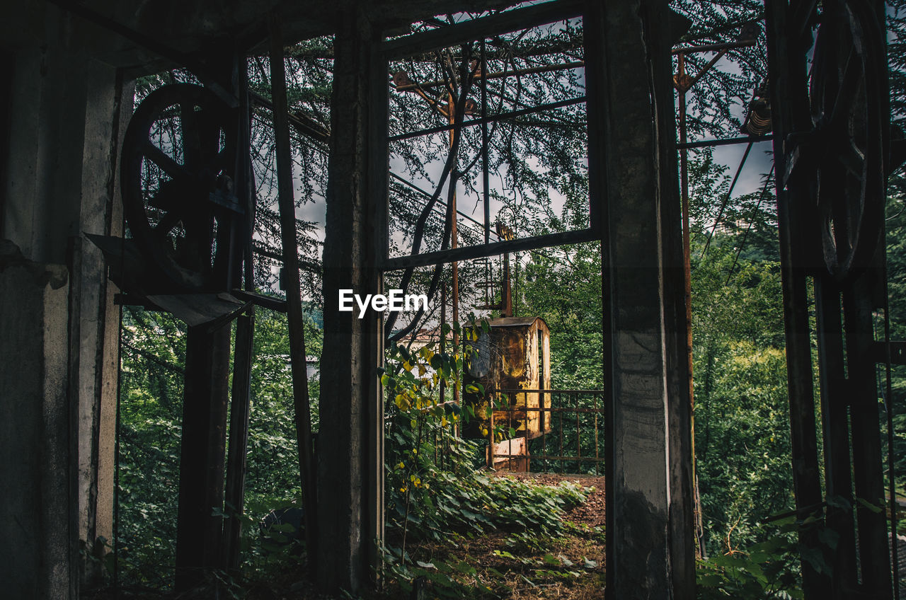 Old rusty overhead cable seen through window hanging in forest