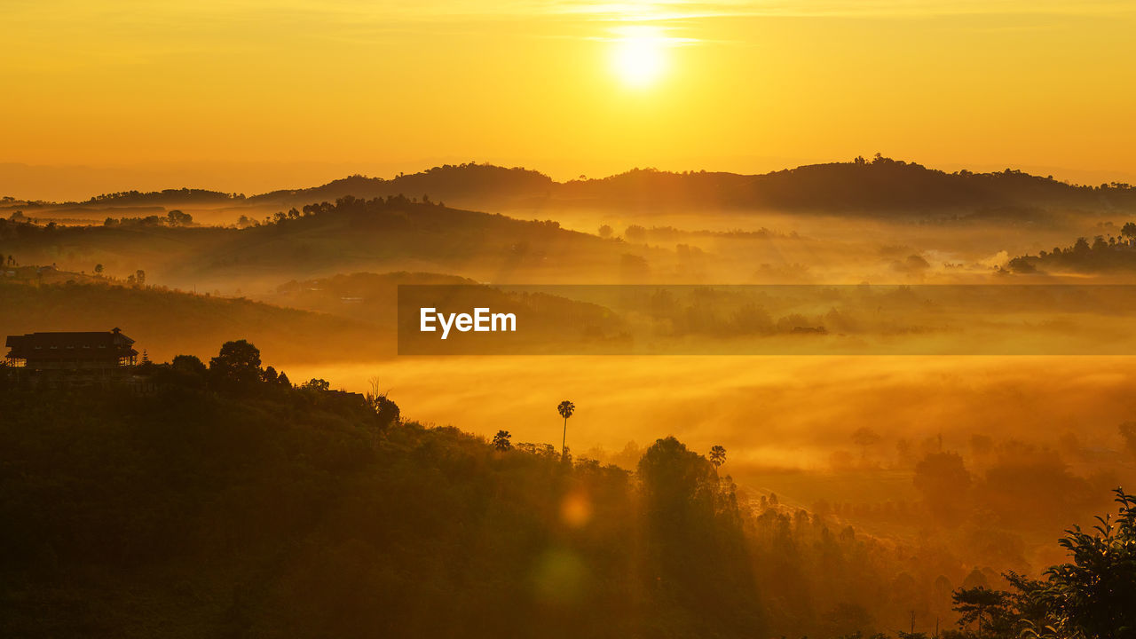 Scenic view of silhouette mountains against orange sky