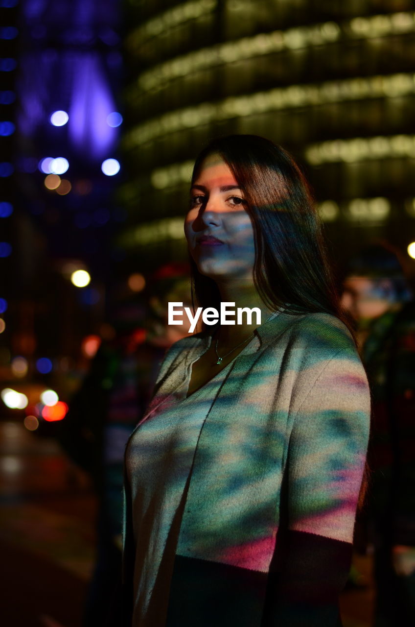 Young woman standing in illuminated city at night