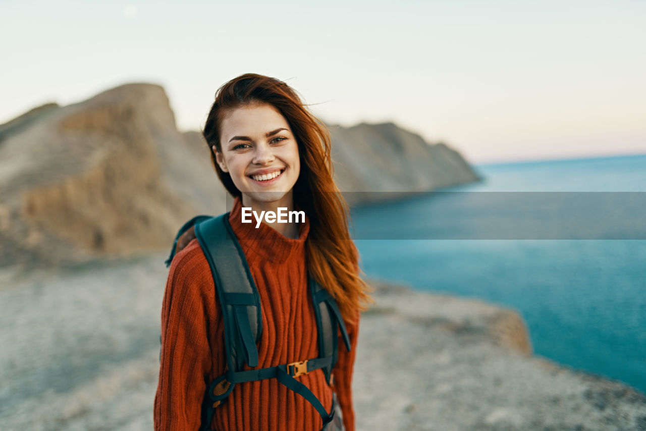 PORTRAIT OF SMILING YOUNG WOMAN STANDING IN SEA