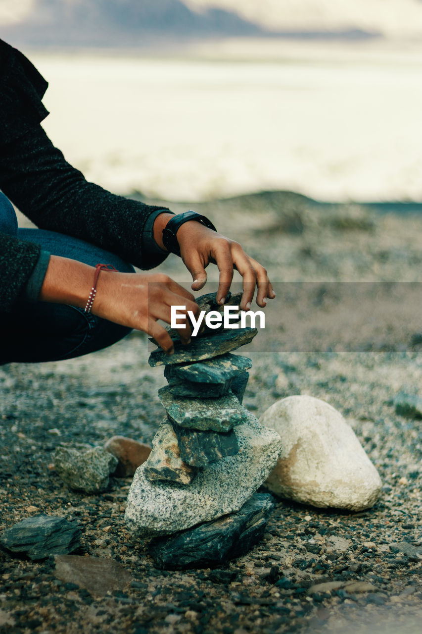 Low section of man stacking stones