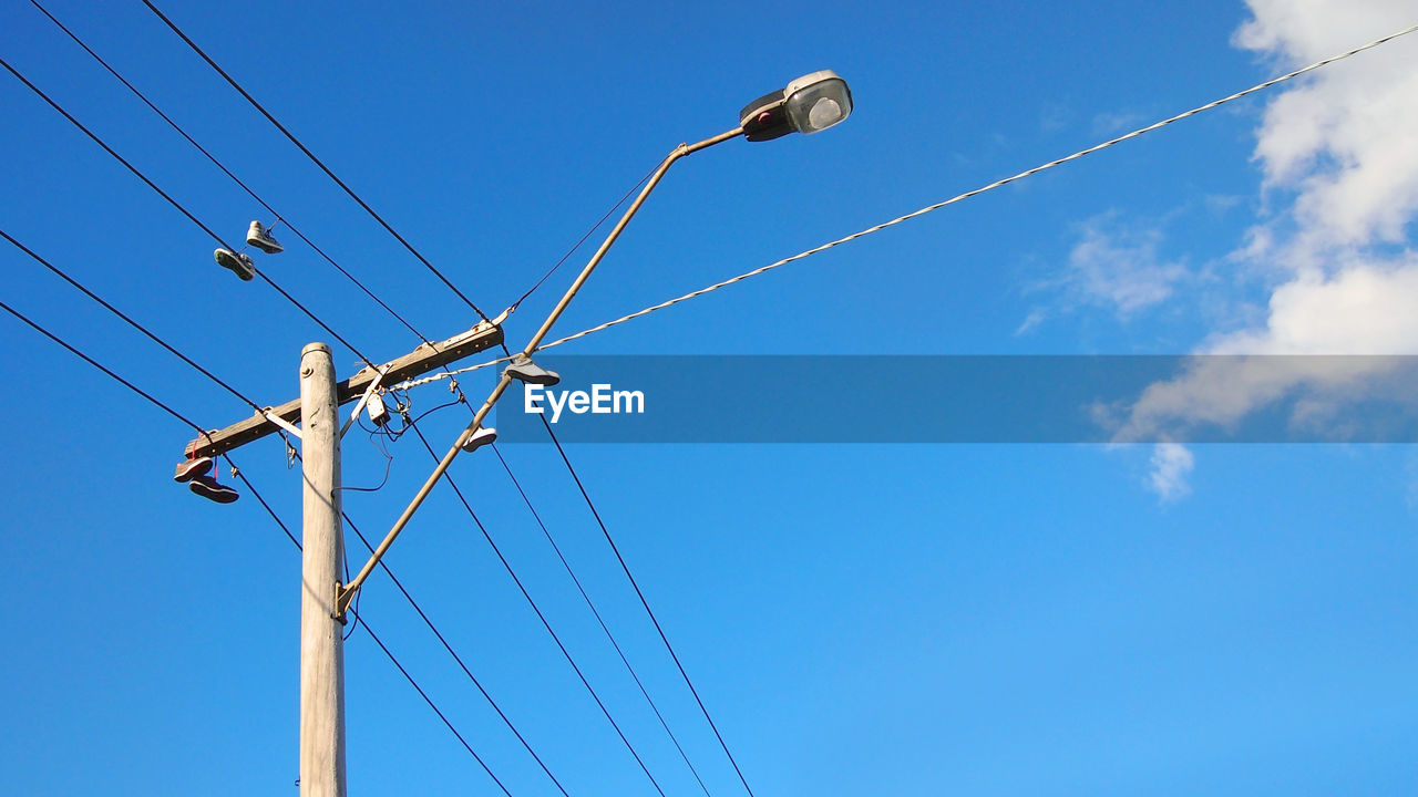 Low angle view of electricity pylon against blue sky