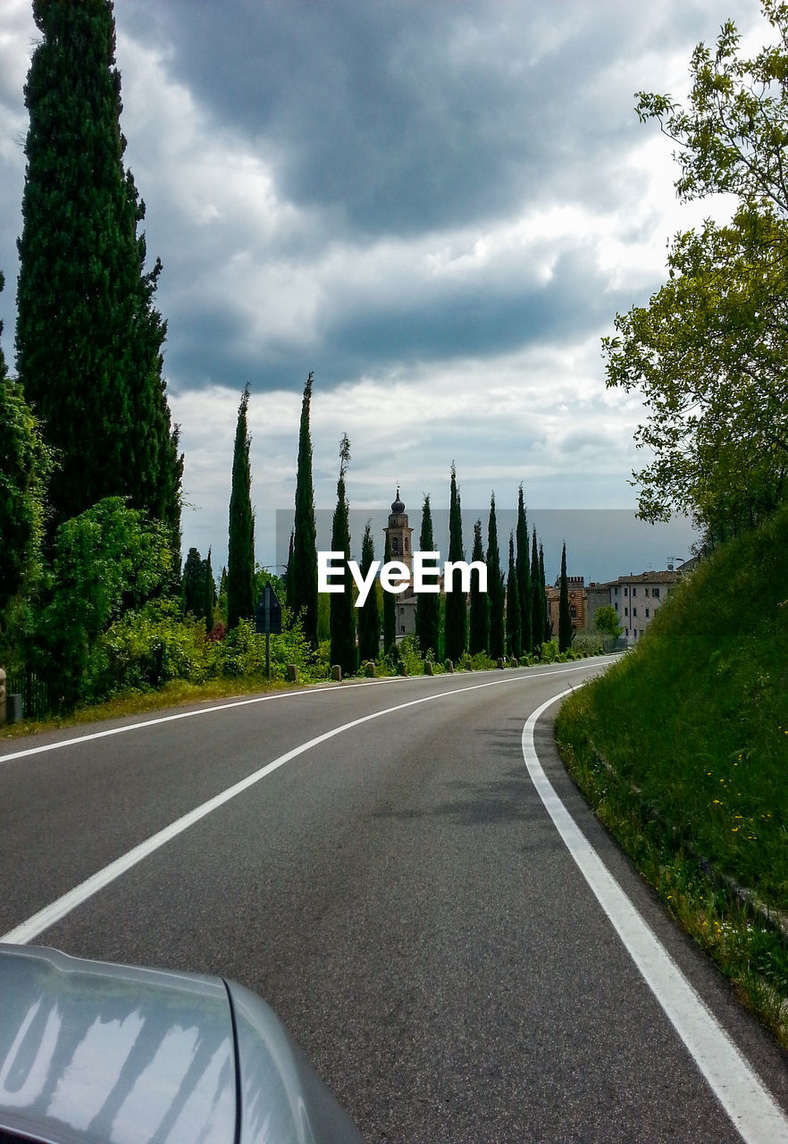 Road by trees against sky