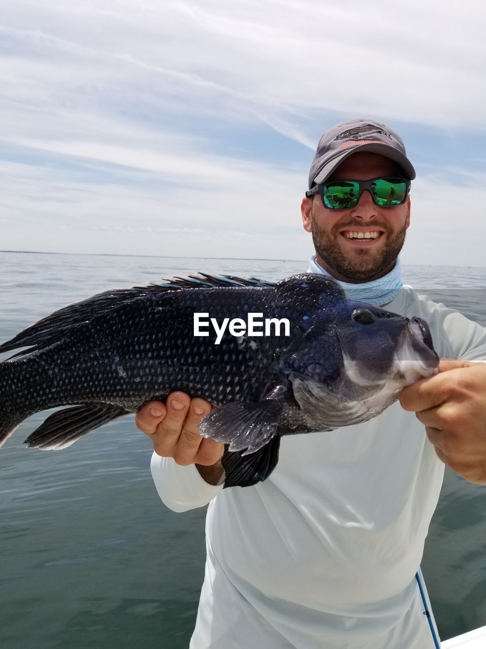 Portrait of man holding fish against sea