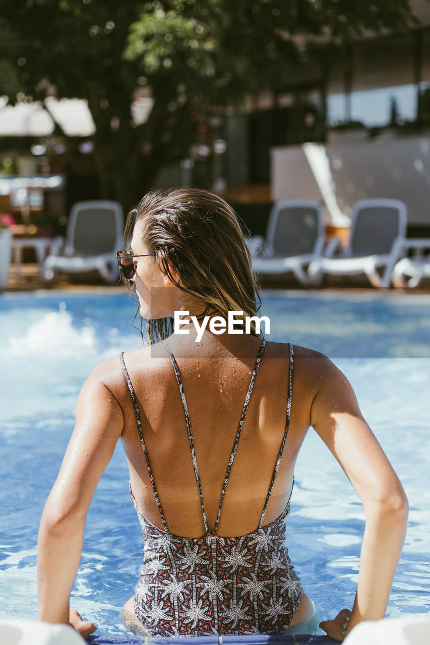 Rear view of woman standing in swimming pool