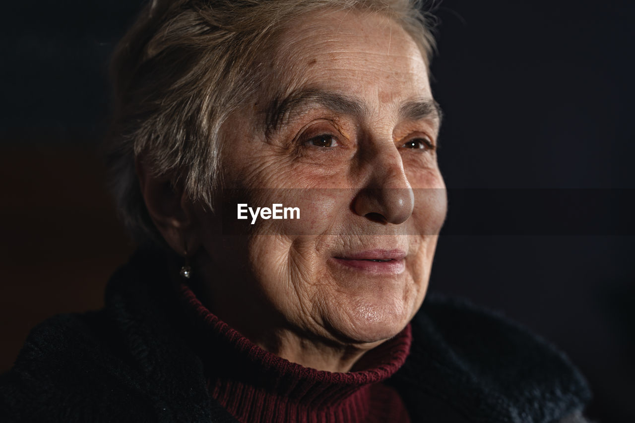 Colroful close-up portrait of senior woman against black background