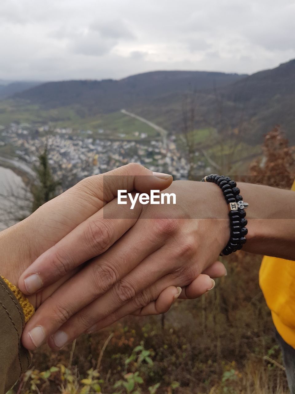 Cropped image of friends holding hands against mountains