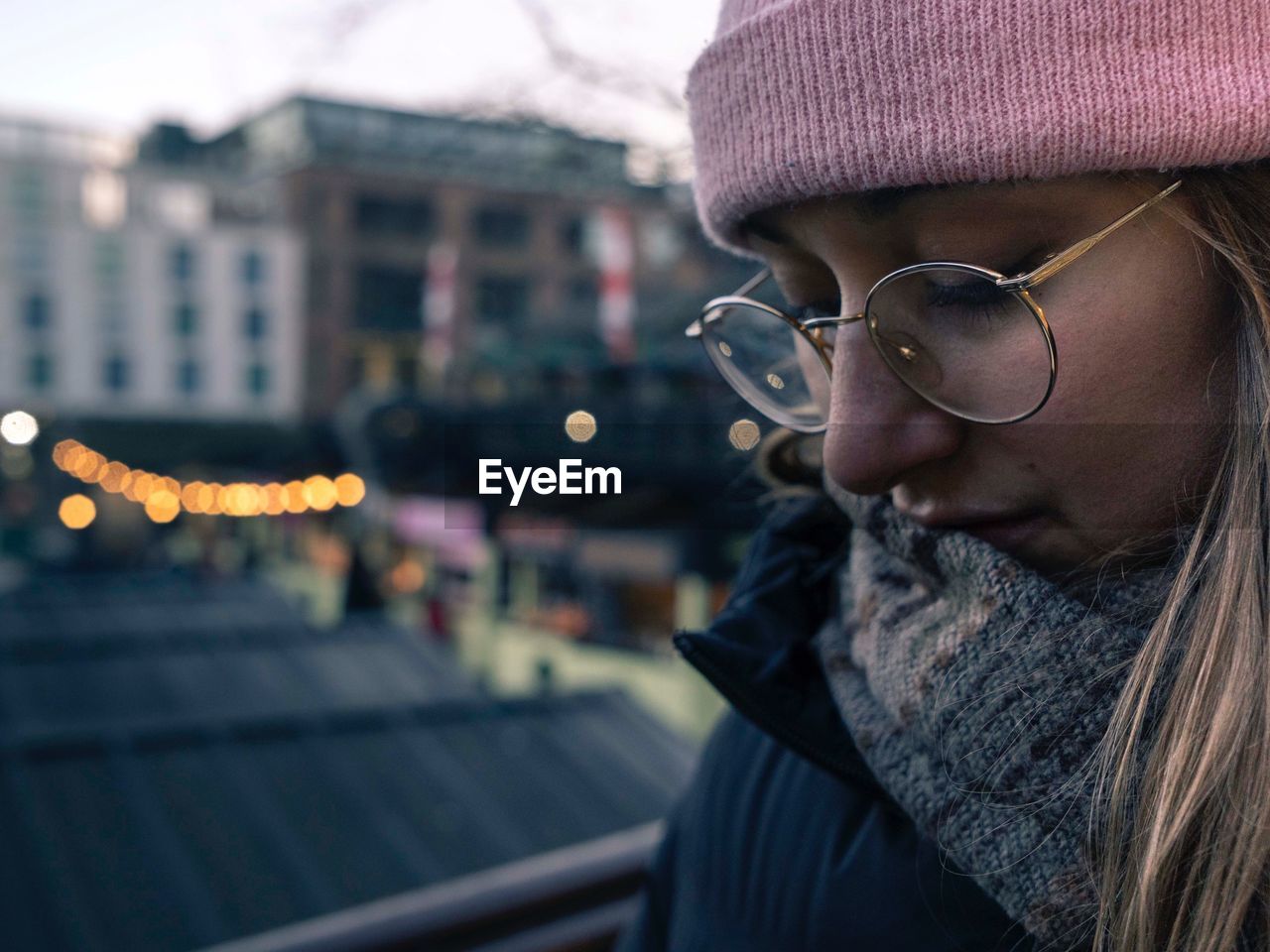 Close-up of young woman wearing eyeglasses standing against buildings in city