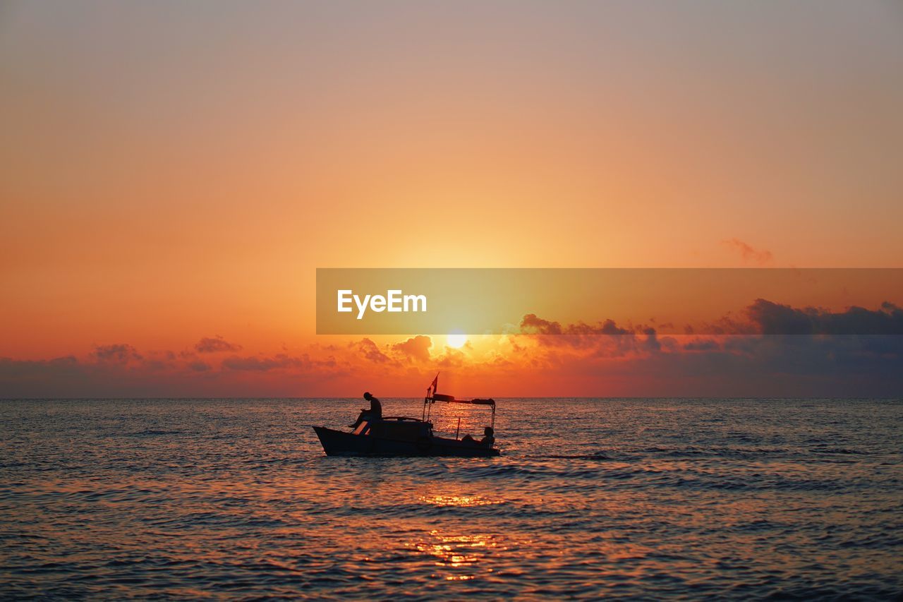 Silhouette boat in sea against sky during sunset