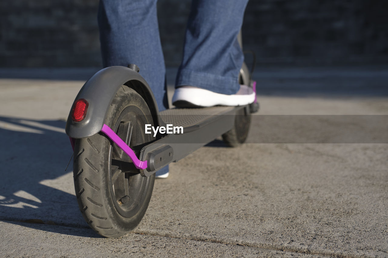 Low section of man standing on push scooter