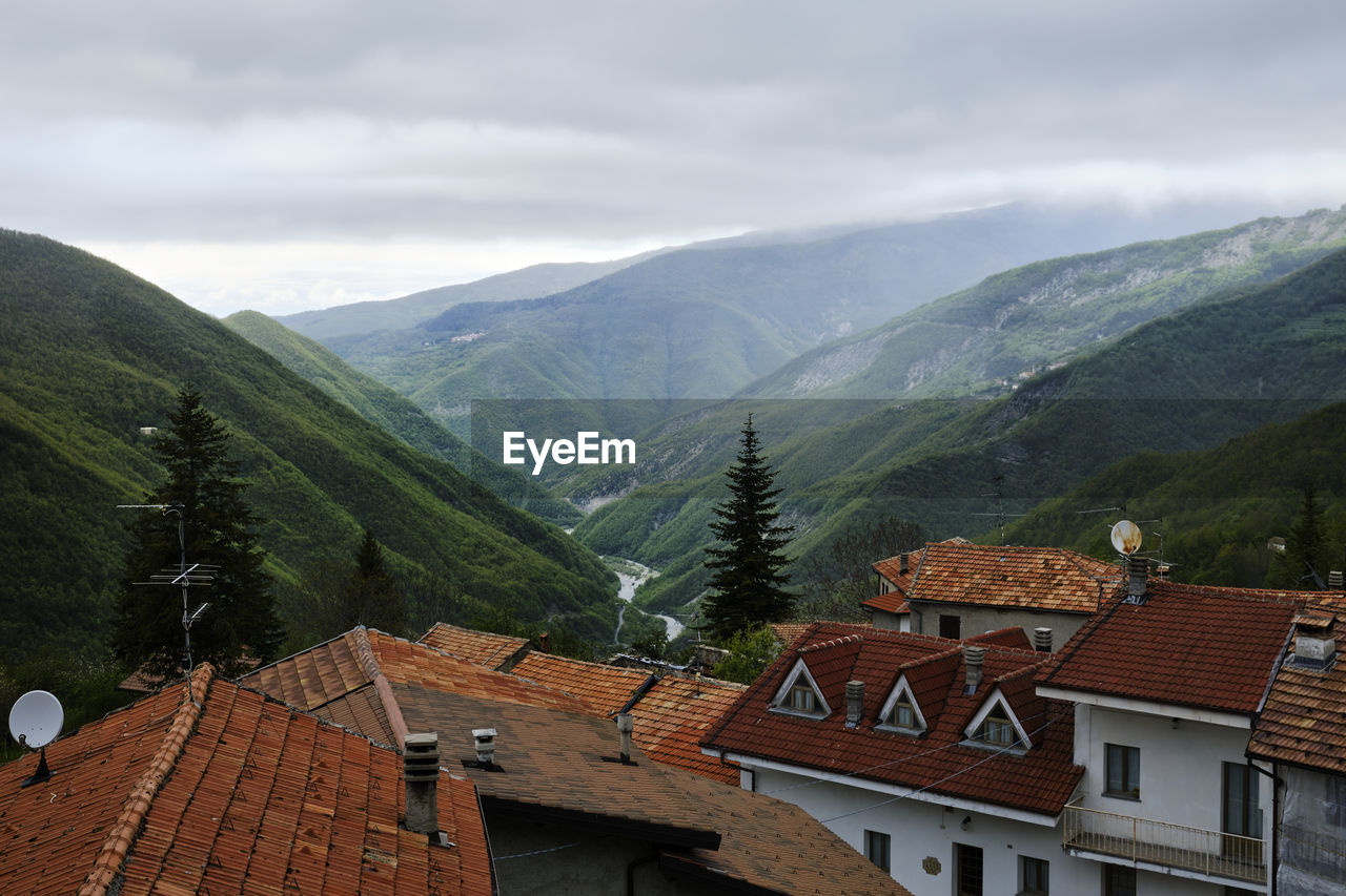 HOUSES ON MOUNTAIN BY ROAD AGAINST SKY