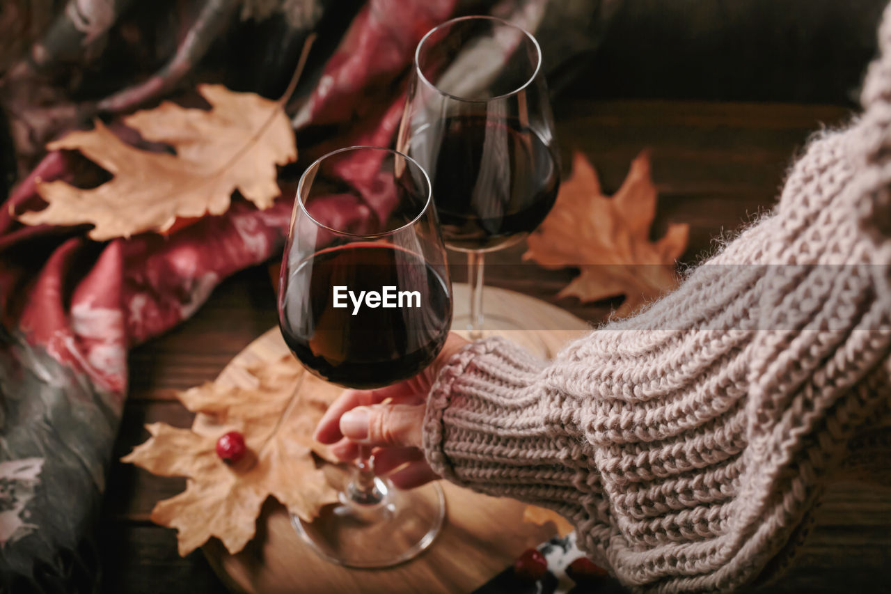 cropped hand of woman holding wineglass on table