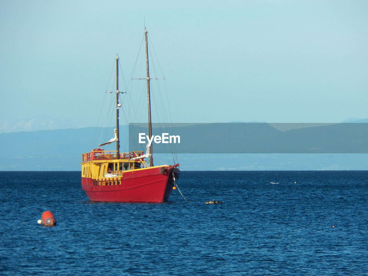 BOAT MOORED IN SEA AGAINST CLEAR SKY