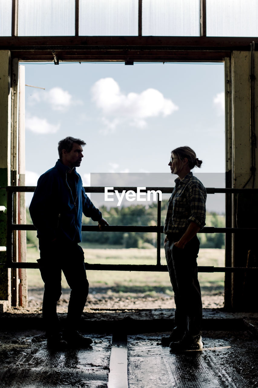 Farmers standing by door and discussing at cattle farm