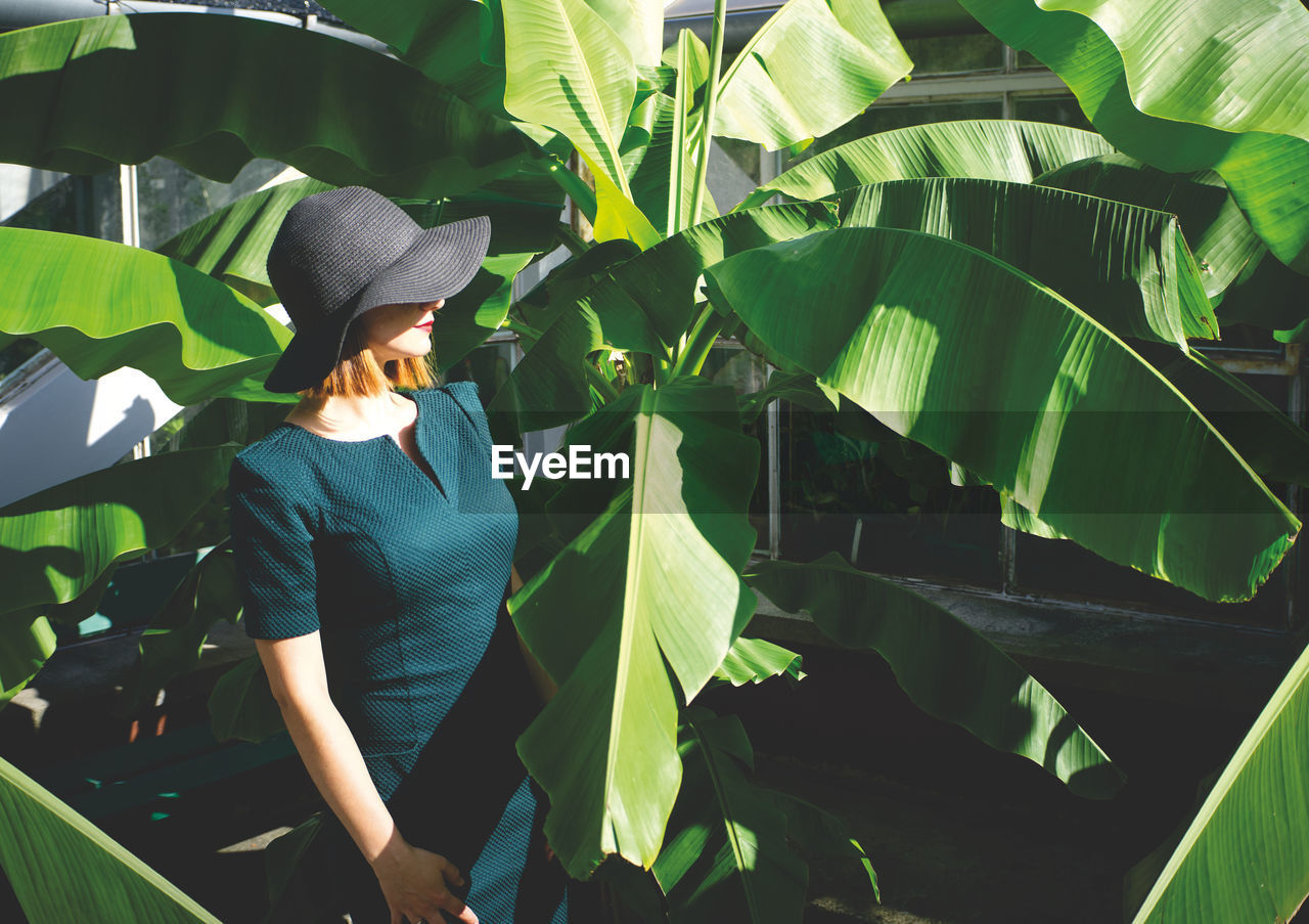 Woman wearing hat standing by plants