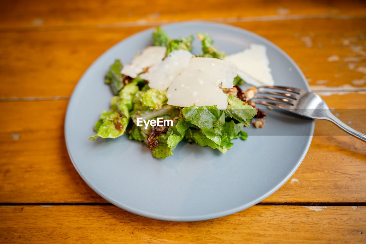 Green vegetable salad with parmesan cheese toppings in a plate.