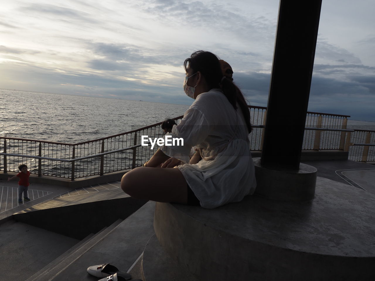 REAR VIEW OF MAN AND WOMAN LOOKING AT SEA