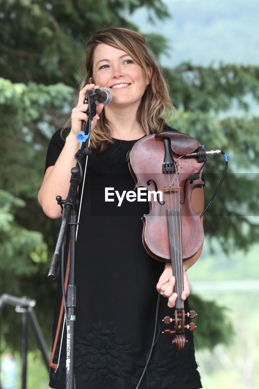 PORTRAIT OF A SMILING YOUNG WOMAN HOLDING CAMERA