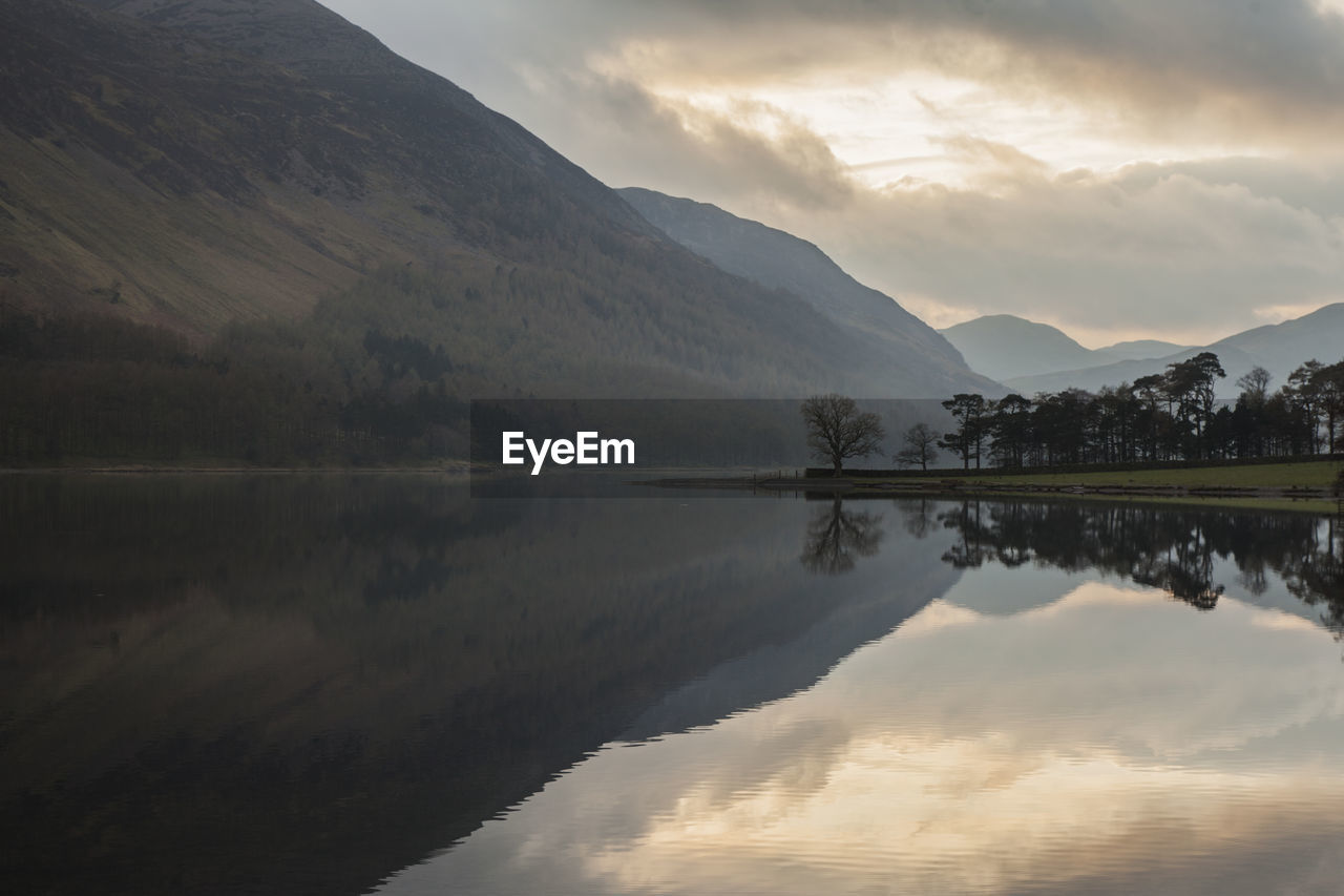 Scenic view of lake by mountains against sky during sunset